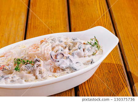 Shrimp and mushroom dish served in a white bowl on wooden table Shrimp and mushroom dish served in a white bowl on wooden table 130375736