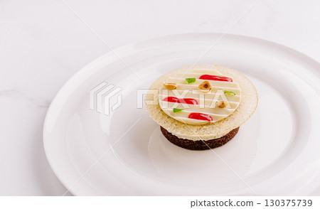 Elegant dessert with layered textures and colorful decorations on a white plate Elegant dessert with layered textures and colorful decorations on a white plate 130375739