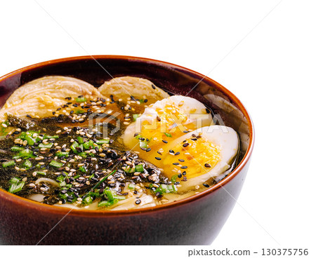 Ramen bowl with soft boiled eggs and garnishes on a white background 130375756