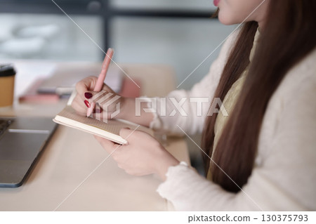 Asian adult freelancer writes notes notebook desk work study planning business remote productivity learning strategy content creation 130375793