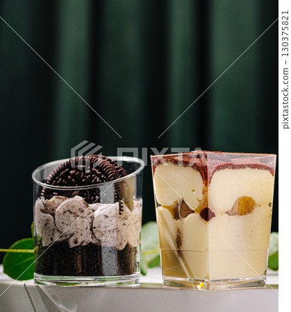 Delicious desserts served in clear glasses with layers of cream and cookies Delicious desserts served in clear glasses with layers of cream and cookies 130375821