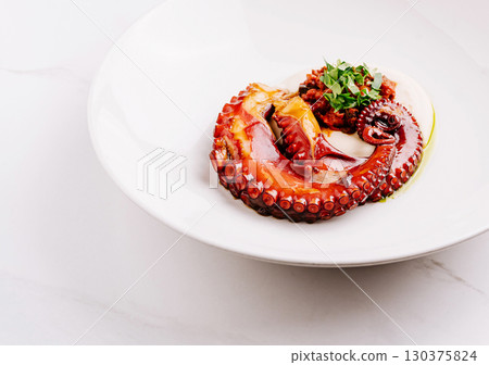 Grilled octopus served on a white plate with fresh herbs and sauce Grilled octopus served on a white plate with fresh herbs and sauce 130375824