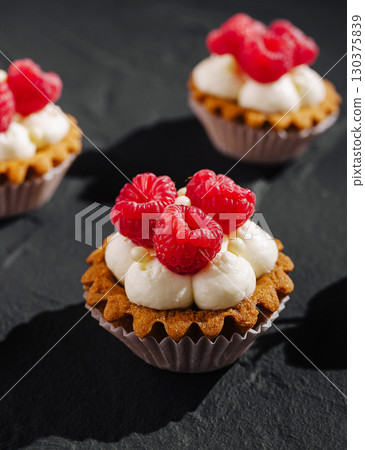 Delicious raspberry tarts with cream served on a dark slate surface Delicious raspberry tarts with cream served on a dark slate surface 130375839