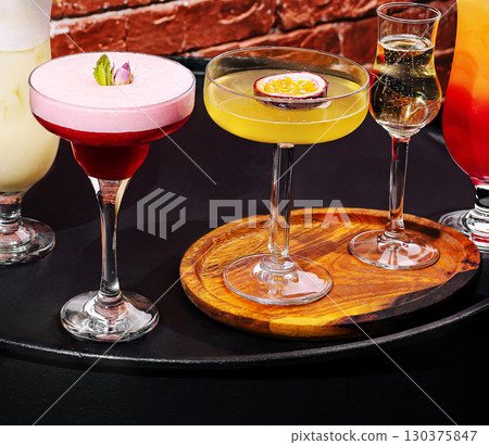 Colorful cocktails served on a wooden tray in a lively bar setting 130375847