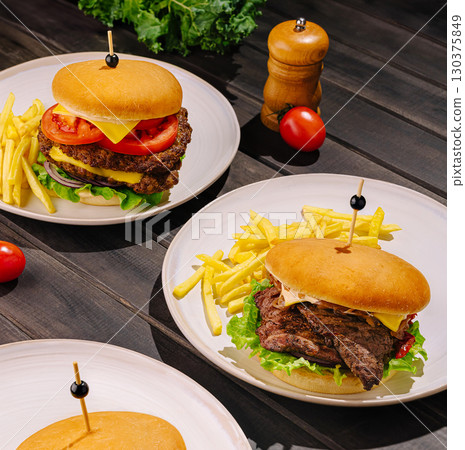 Gourmet burgers with fries served on wooden table at casual eatery Gourmet burgers with fries served on wooden table at casual eatery 130375849