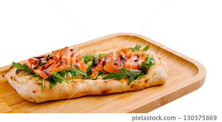 Tasty flatbread with smoked salmon and greens on a wooden board 130375869