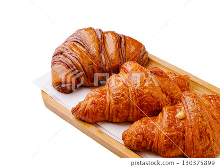 Freshly baked croissants arranged on a wooden tray with a warm glow 130375899