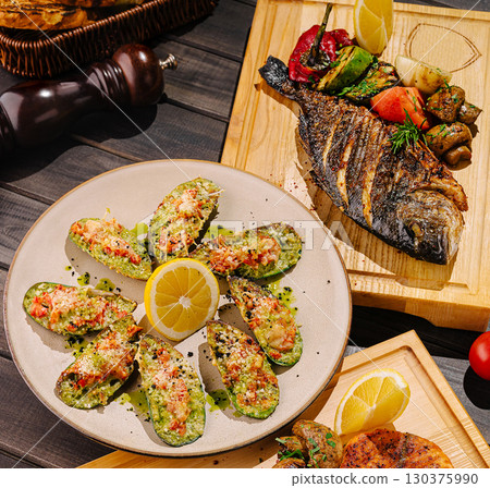 Seafood platter with grilled fish and stuffed shells on wood table 130375990