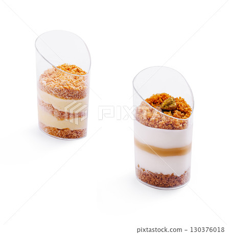Desserts displayed in transparent cups with layered cream and crumbs 130376018