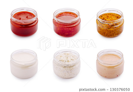 Various sauces and condiments in jars arranged on a white background 130376050