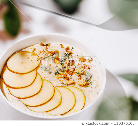 Delicious oatmeal topped with pears and nuts served in a bright kitchen 130376103