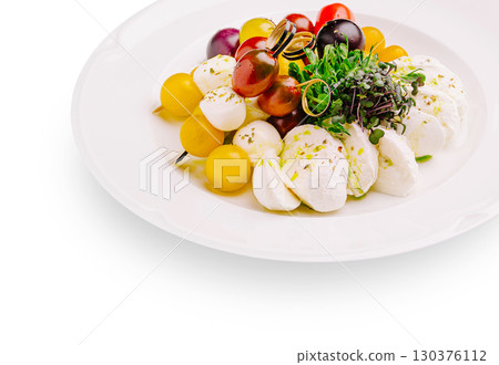 Fresh mozzarella salad with colorful grapes and microgreens on a white plate 130376112