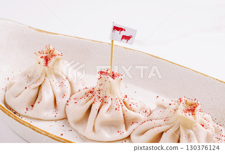 Unique dumplings garnished with red spice and a small flag 130376124