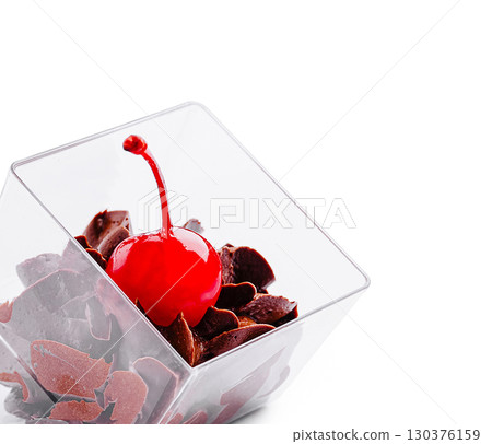 Dessert with chocolate shavings and a cherry on top in a glass container Dessert with chocolate shavings and a cherry on top in a glass container 130376159