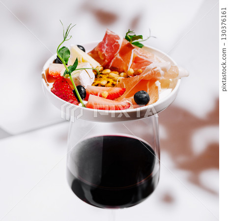Fresh fruit and gourmet toppings served with dark wine at a modern table 130376161