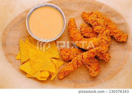 Crispy fried shrimp tenders with nachos and dipping sauce served on a platter Crispy fried shrimp tenders with nachos and dipping sauce served on a platter 130376163