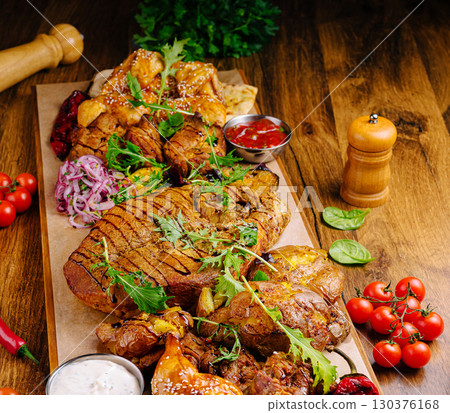 Delicious platter of roasted meats and fresh vegetables at a rustic table 130376168