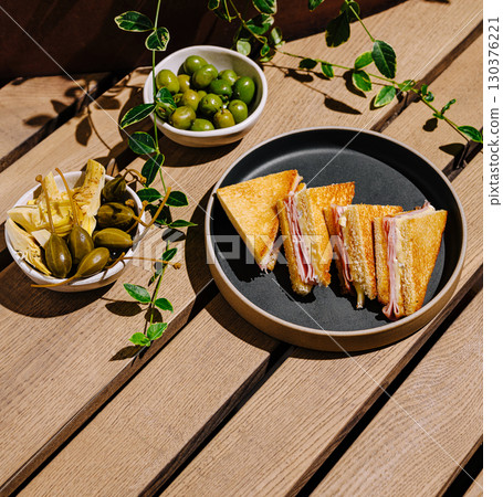 Delicious ham and cheese sandwich served on wooden table with olives 130376221