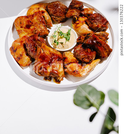Grilled chicken platter served with dipping sauce on a white background Grilled chicken platter served with dipping sauce on a white background 130376222