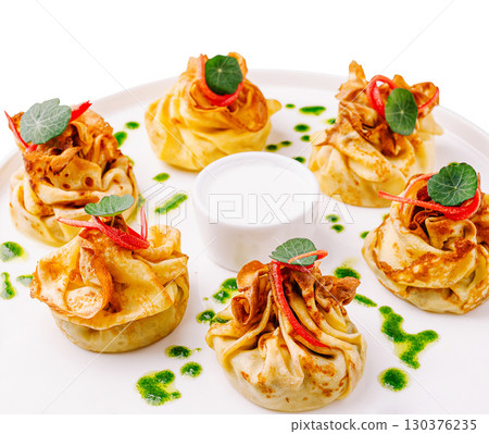 Delicate savory pastries served with sauce on a white plate 130376235