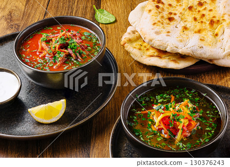 Delicious bowls of soup served with warm flatbread and lemon slice 130376243