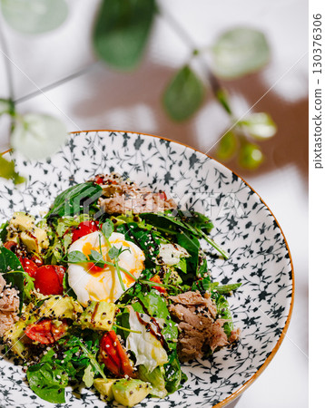 Fresh mixed salad with poached egg and vibrant ingredients in a bowl 130376306