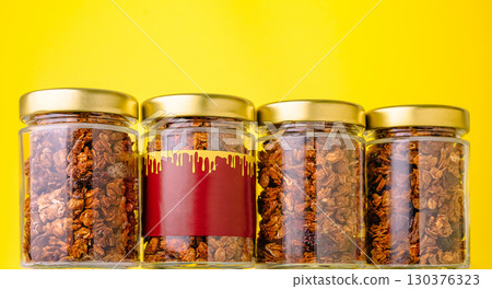 Granola jars on a bright yellow backdrop showcase healthy snacks 130376323