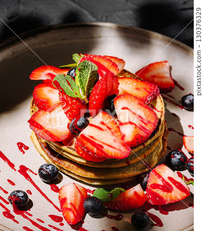 Delicious pancake stack topped with fresh strawberries and blueberries 130376329