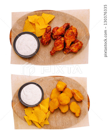 Delicious platter of chicken wings and crispy snacks served with dipping sauce Delicious platter of chicken wings and crispy snacks served with dipping sauce 130376335