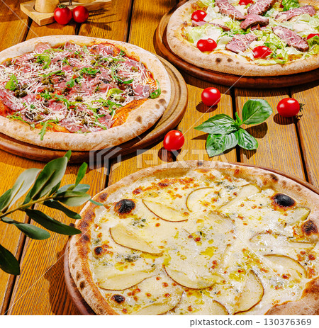 Delicious assortment of gourmet pizzas with fresh ingredients on wooden table 130376369