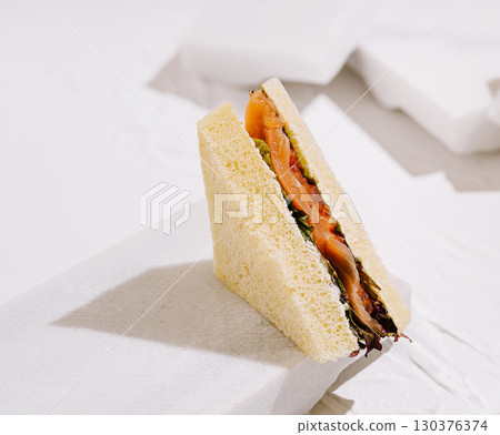 Delicious sandwich with smoked salmon and fresh greens on a light background 130376374
