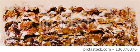 Delicious layered dessert with nuts and cream served on a white plate 130376376