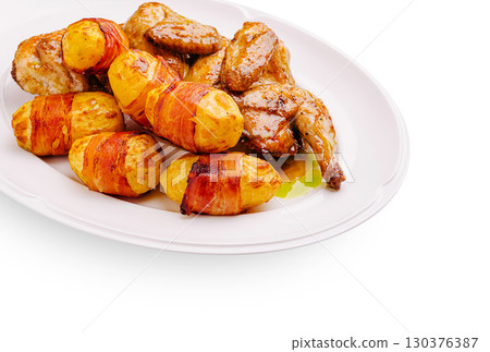 Delicious roasted chicken with bacon-wrapped potatoes served on a platter Delicious roasted chicken with bacon-wrapped potatoes served on a platter 130376387