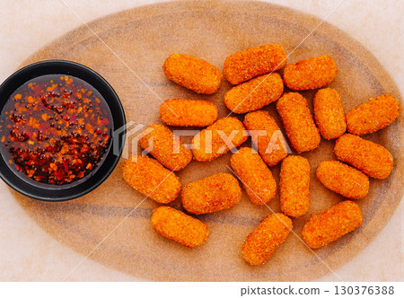Delicious golden croquettes served with spicy dipping sauce on wooden platter 130376388