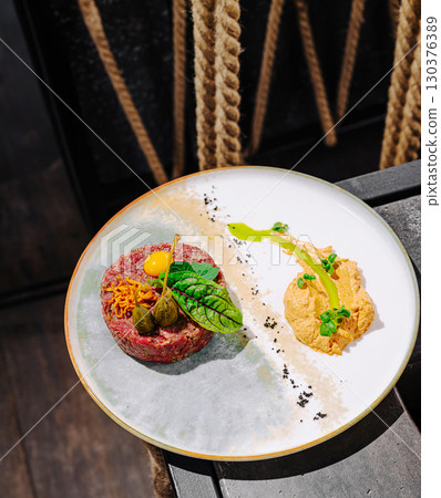 Gourmet dish of beef tartare with egg yolk and creamy spread on elegant plate 130376389
