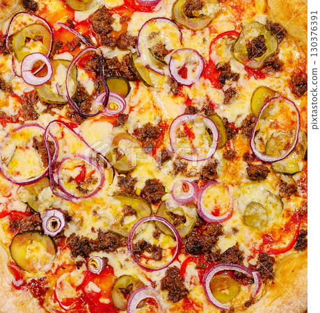 Savory pizza topped with beef, onions, and pickles served fresh out of the oven Savory pizza topped with beef, onions, and pickles served fresh out of the oven 130376391
