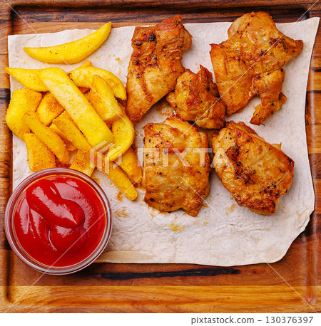 Crispy fried chicken, golden fries, and tangy sauce on a wooden board 130376397