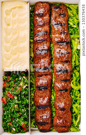 Delicious skewers of grilled kebabs served with fresh salads and hummus Delicious skewers of grilled kebabs served with fresh salads and hummus 130376438