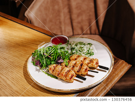 Delicious grilled pork skewers served with fresh salad and dipping sauce Delicious grilled pork skewers served with fresh salad and dipping sauce 130376456