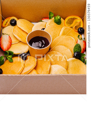 Delicious pancake assortment with fresh fruits and syrup served in a box 130376459