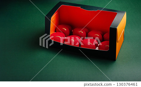 Elegant gift box filled with round red mousse desserts, decorated with a golden accent 130376461