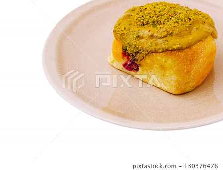 Freshly baked pastry topped with pistachio and creamy filling on a plate 130376478