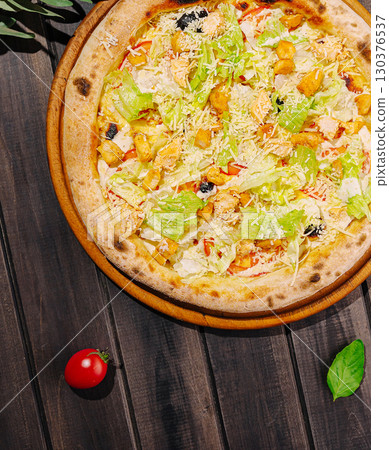 Freshly made pizza topped with greens and chicken on a wooden table Freshly made pizza topped with greens and chicken on a wooden table 130376537