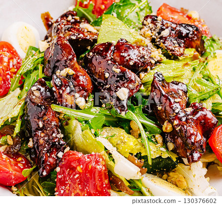 Colorful salad featuring greens, cherry tomatoes, and glazed meat topping Colorful salad featuring greens, cherry tomatoes, and glazed meat topping 130376602