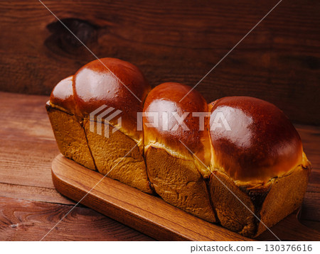 Freshly baked soft bread loaf on wooden board ready for slicing 130376616