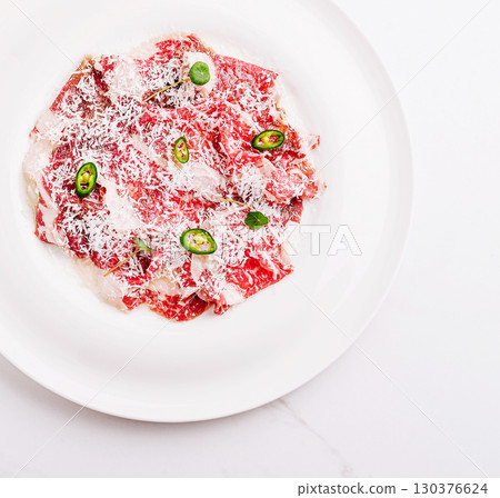 Delicious beef carpaccio with jalapenos and cheese served on a white plate Delicious beef carpaccio with jalapenos and cheese served on a white plate 130376624