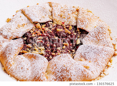 Sweet pastry dessert with fruit filling and nut topping presented invitingly 130376625