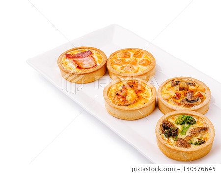 Delicious variety of savory mini quiches on a white plate 130376645