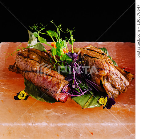 Grilled steak garnished with fresh herbs and edible flowers on salt block Grilled steak garnished with fresh herbs and edible flowers on salt block 130376647