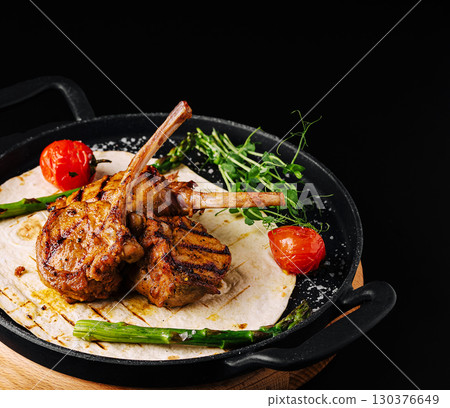 Grilled lamb chops served with vegetables on a sizzling platter Grilled lamb chops served with vegetables on a sizzling platter 130376649